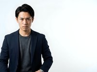 Young Asian male professional wearing navy blazer and gray t-shirt, standing against white background. Suitable for corporate, business, and lifestyle design projects.