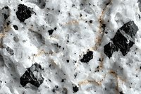 Close-up view of natural granite texture showing black mineral inclusions in white crystalline matrix with subtle orange veining creating abstract pattern.