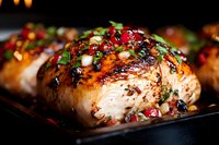 Juicy grilled salmon fillet garnished with fresh herbs, pomegranate seeds and Asian-inspired glaze on dark background, close up view with selective focus.