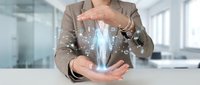 Professional businesswoman in beige suit protecting glowing digital human hologram with hands in modern office environment for healthcare technology concepts.