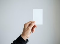 Male hand holding blank white card against neutral background, suitable for branding, business card mockups, and promotional material presentations.