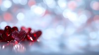 Red glittering hearts on reflective surface against soft bokeh background in silver and pink tones, romantic Valentine's Day concept for greeting cards and designs.