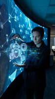 Male professional of mixed ethnicity in business attire interacting with holographic AI interface displaying digital network connections and data visualization in modern tech environment.