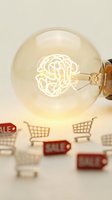 Glowing lightbulb with brain-shaped filament above miniature shopping carts and sale tags representing creative marketing ideas and consumer psychology concepts.