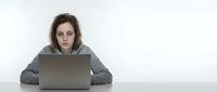 Exhausted young Caucasian woman with messy hair and dark circles sitting at laptop, looking stressed and overwhelmed, burnout and mental fatigue concept.