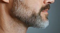 Close-up profile of mature man with well-groomed gray beard and mustache showing facial hair texture and masculine grooming style for barbershop concepts.