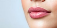Close up of plump, glossy pink lips on smooth skin against light background, showcasing natural beauty makeup and professional cosmetic application technique.