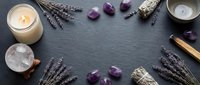 Spa wellness flat lay with lavender sprigs, amethyst crystals, sage bundles and candles on dark slate background for relaxation and meditation rituals.