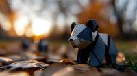 Black geometric origami panda figure on autumn forest ground with fallen leaves and warm sunset bokeh background creating magical atmosphere.