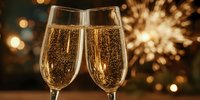 Two champagne flutes with golden bubbling wine against blurred background with festive bokeh lights and fireworks for celebration.