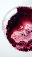 Overhead view of crushed magenta and burgundy powder pigment with textured granules scattered across white surface, suitable for cosmetics and beauty product photography.