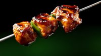 Grilled chicken kebab with peppers on skewer against dark background. Juicy barbecue meat with vegetables for restaurant menu, cooking blog, food advertising.