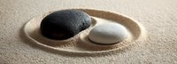 Black and white stones on sand in circular pattern, symbolizing balance and harmony for meditation, wellness, and spa environments.