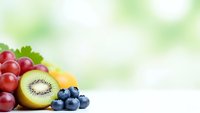 Fresh mixed fruits including red grapes, sliced kiwi and blueberries on soft green bokeh background with copy space for healthy eating and nutrition concepts.