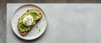 Avocado toast with poached egg on whole grain bread served on white plate, overhead flat lay for food blogging and restaurant menus.