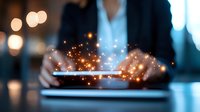 Digital tablet with magical glowing light effects in businessperson hands against dark background with bokeh lights, showcasing modern technology innovation.