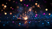 Bright sparkler burning against dark background with colorful bokeh lights and glitter creating magical festive atmosphere for celebration designs.