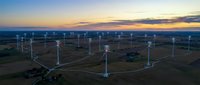 Aerial view of wind turbines generating renewable energy at sunset with connected network lines showing smart grid technology and sustainable power distribution.