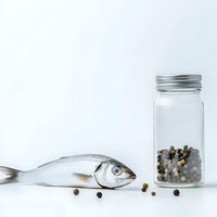 Fresh raw fish with peppercorns in glass jar on white background. Culinary ingredients for cooking seafood dishes and gourmet recipes preparation.