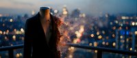 Man in business suit standing on rooftop overlooking illuminated cityscape at dusk, head dissolving into golden light particles and bokeh effects, representing transformation and success.