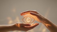Hands protecting glowing eye symbol, representing vision care, insight, awareness, and spiritual enlightenment for wellness and mindfulness concepts.