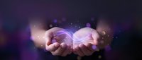 Cupped hands holding glowing purple energy orb with magical light particles and bokeh effects against dark background for spiritual and mystical concepts.