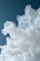 White soap foam bubbles macro photography against dark blue background creates abstract texture pattern with delicate details and soft lighting effects.