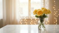 Yellow roses in glass vase on white table with warm bokeh lights creating cozy home interior atmosphere for romantic decor and floral arrangements.