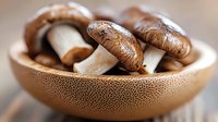 Fresh brown mushrooms in textured ceramic bowl, macro food photography with selective focus on raw organic produce showing natural texture and detail.