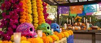 Colorful decorated skulls with marigold flowers for Day of the Dead celebration at traditional Mexican market stall with papel picado banners.