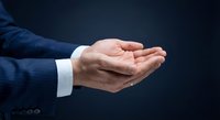 Businessman cupped hands gesture on dark background showing protection, care and support concept for presentations and marketing materials.