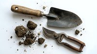Gardening hand tools with soil and dirt scattered on white background, suitable for landscaping, agriculture, and outdoor work projects.