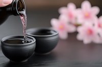 Traditional Japanese sake being poured into ceramic cups with cherry blossoms creating elegant cultural dining atmosphere for restaurant menus.