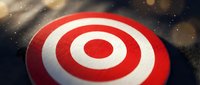 Red and white bullseye target with concentric circles on dark background with bokeh lights for business goals and achievement concepts.