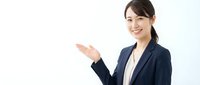 Professional Asian businesswoman in navy suit presenting with open hand gesture against white background for corporate presentations.