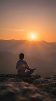Woman meditating in lotus pose on mountain peak during golden sunrise with layered mountain ranges creating peaceful spiritual wellness moment.