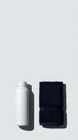 Blank white insulated bottle and folded dark navy towel on neutral background, isolated for product mockups, branding, and lifestyle design applications.