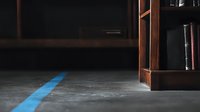 Mysterious blue light beam on concrete floor near wooden bookshelf in dark room creates dramatic atmosphere. Minimalist composition with strong contrast.