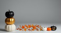 Stacked black, gold, and white pumpkins with autumn leaves and small gourds on gray background for fall decorating and seasonal design projects.
