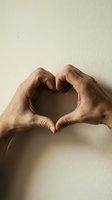 Hands forming a heart shape against a neutral wall, symbolizing love, care, and connection for Valentine's Day or wellness campaigns.