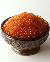 Fresh red caviar in vintage silver bowl with ornate floral pattern, bright orange salmon roe pearls on light background, gourmet seafood delicacy.