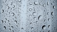 Water droplets on glass surface creating natural condensation pattern for backgrounds and textures.