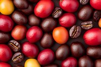 Colorful mix of fresh coffee beans and ripe coffee cherries in red, yellow and orange hues creating vibrant food background pattern, macro photography.
