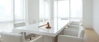 Modern minimalist conference room with white table, leather chairs and wooden gavel for legal meetings, corporate boardroom interior with natural light.