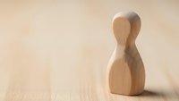 Wooden pawn figure standing alone on light surface symbolizing leadership, individuality and business strategy concepts for presentations.