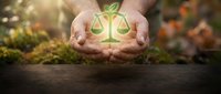 Hands holding glowing scales of justice symbol over natural earth background, representing law, ethics, environmental protection, sustainability and legal responsibility.