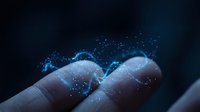 Glowing blue digital particles flowing over human fingertips on dark background, representing data, technology, and futuristic connectivity.
