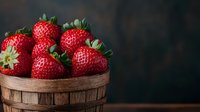 Fresh ripe strawberries in rustic wooden basket against dark background, moody food photography with natural lighting and copy space.
