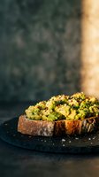 Avocado toast with seeds and herbs on rustic bread served on dark slate plate. Healthy breakfast or brunch meal with fresh ingredients and natural lighting.