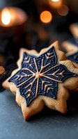 Decorated gingerbread snowflake cookie with intricate blue icing pattern on dark surface with warm bokeh lights creating festive holiday atmosphere.